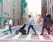 Two families are crossing the street with a stroller and scooter.